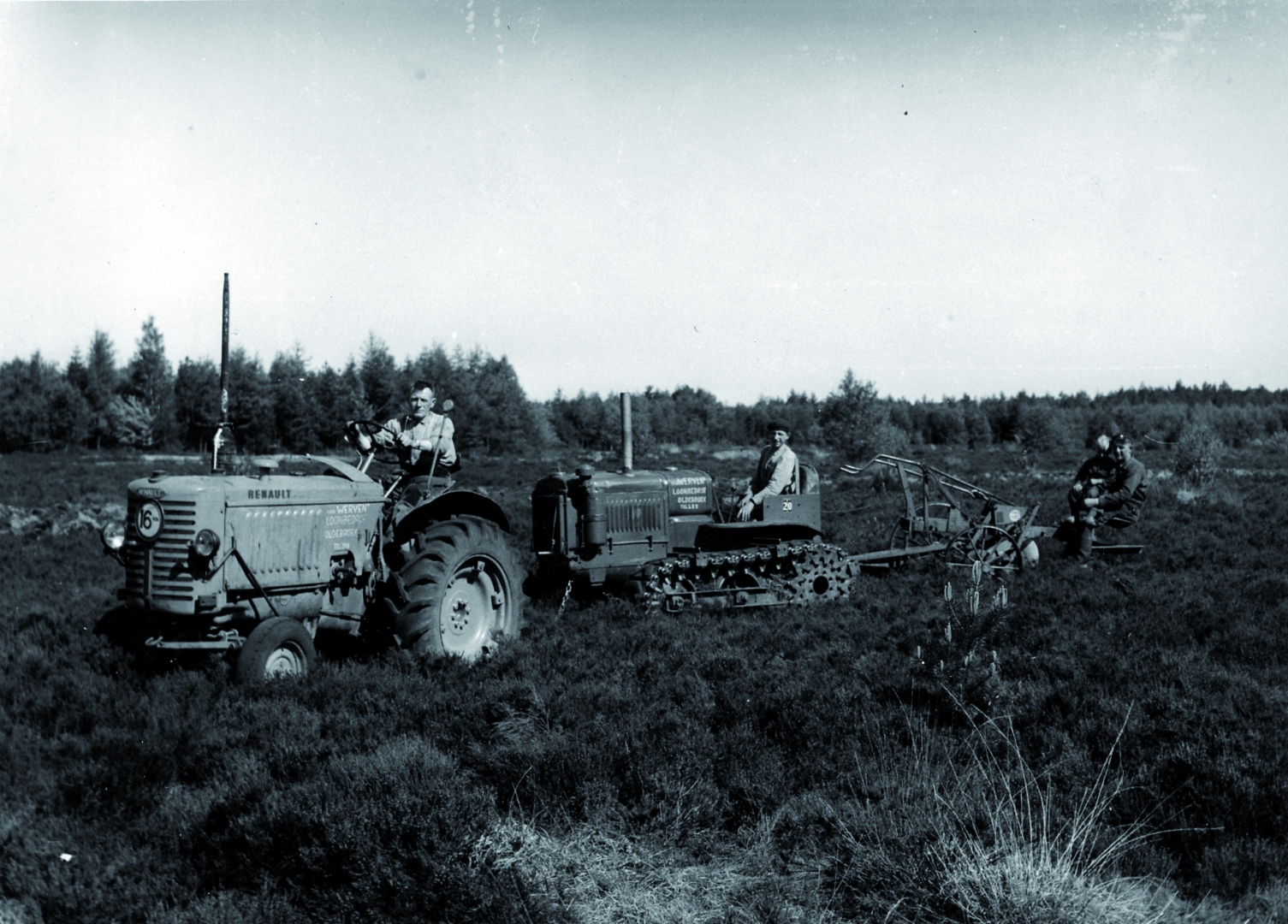 Zwart-witfoto uit de beginjaren: een Renault-trekker en een rupstrekker van loonbedrijf Van Werven ploegen heidegrond, drie mannen kijken toe