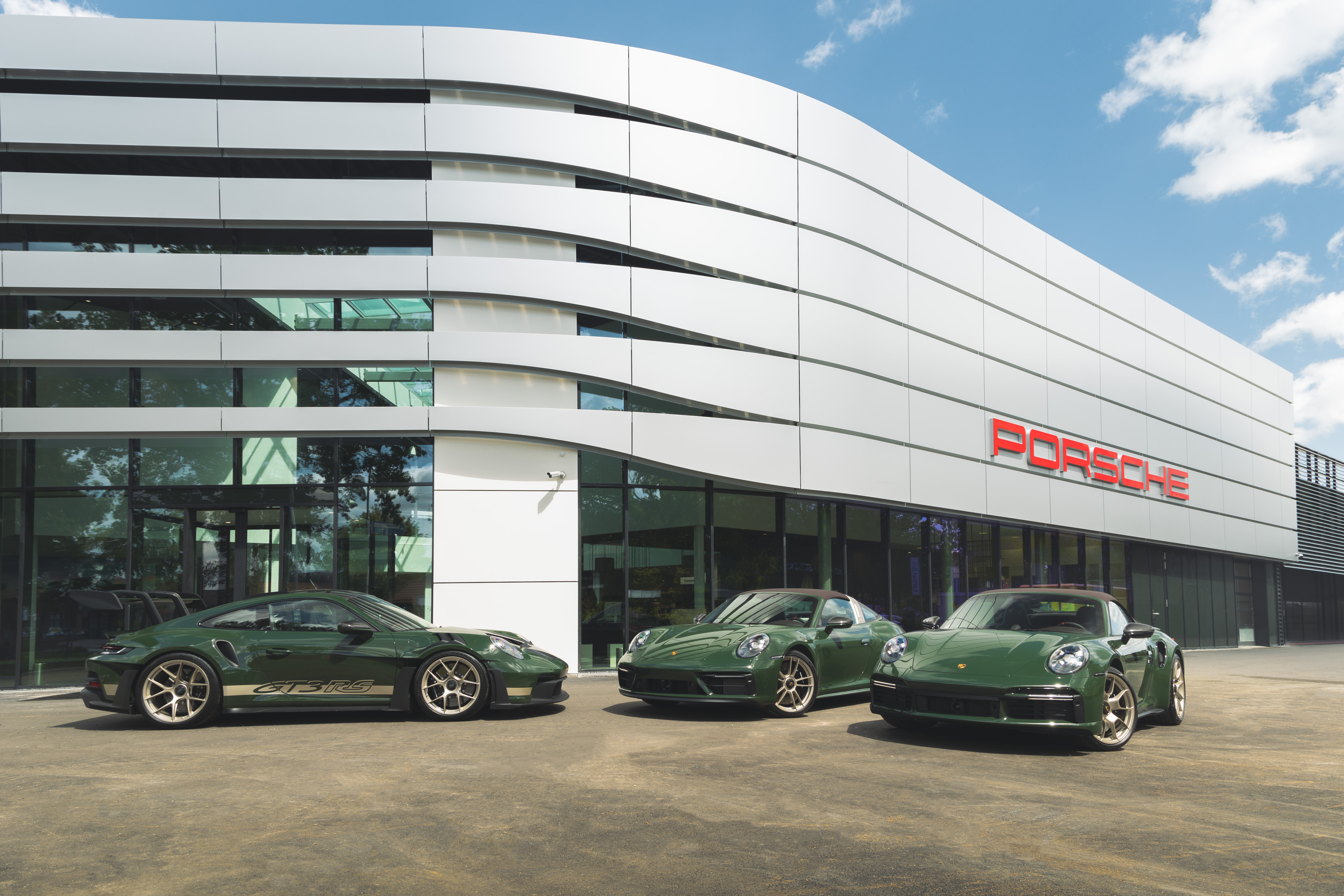 De nieuwe vestiging van Porsche Centrum Brabant, met drie donkergroene Porsche 911’s voor de showroom.