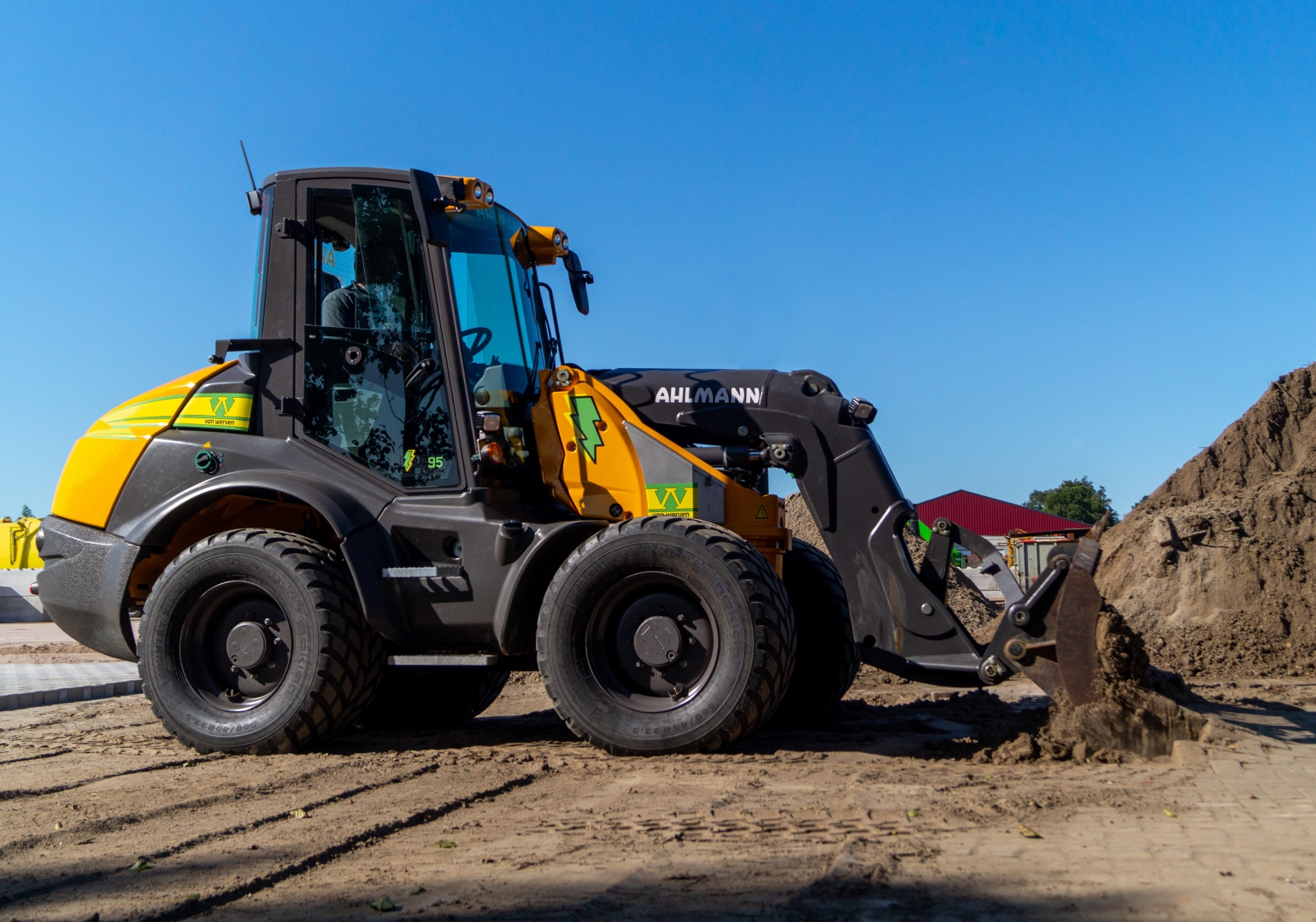 De elektrische Ahlmann shovel van Van Werven aan het werk op het zand